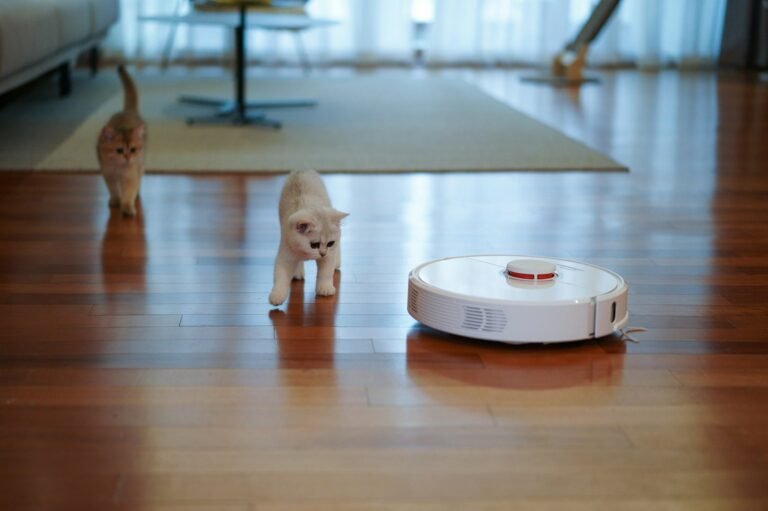 White robot vacuum cleaner rolling across a shiny wooden floor in a bright living room